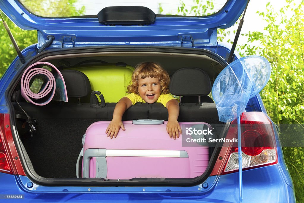 Happy boy with bags in the car Boy sitting on the back sit with bags and other luggage in the car trunk happy and laughing ready to go on the trip 2-3 Years Stock Photo