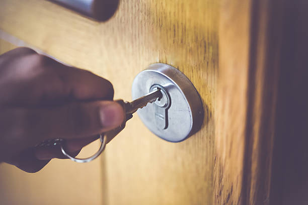 Door Lock & Key Man opening the door to his home with his steel key. lock photos stock pictures, royalty-free photos & images