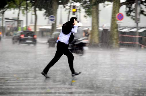 Man running in the rain and crossing the street