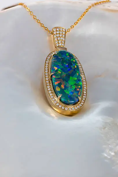 Exquisite opal gemstone jewelery set inside gold plate with diamonds photographed on a shell. 