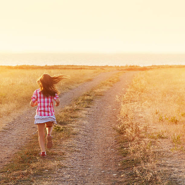 istock Little girl running in backlit meadow 478371807