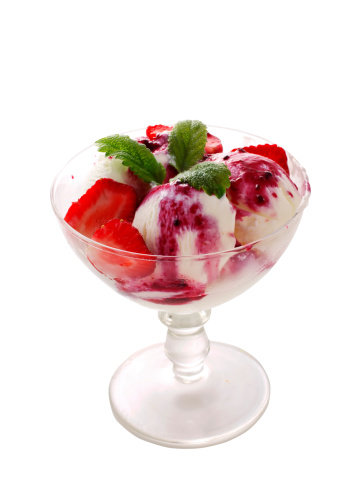 Ice cream with jam and fruits in glass bowl over white