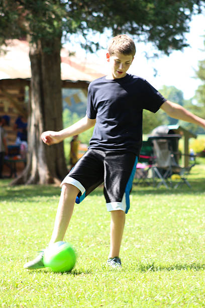 istock Teenager Kicks Soccer Ball 478377456