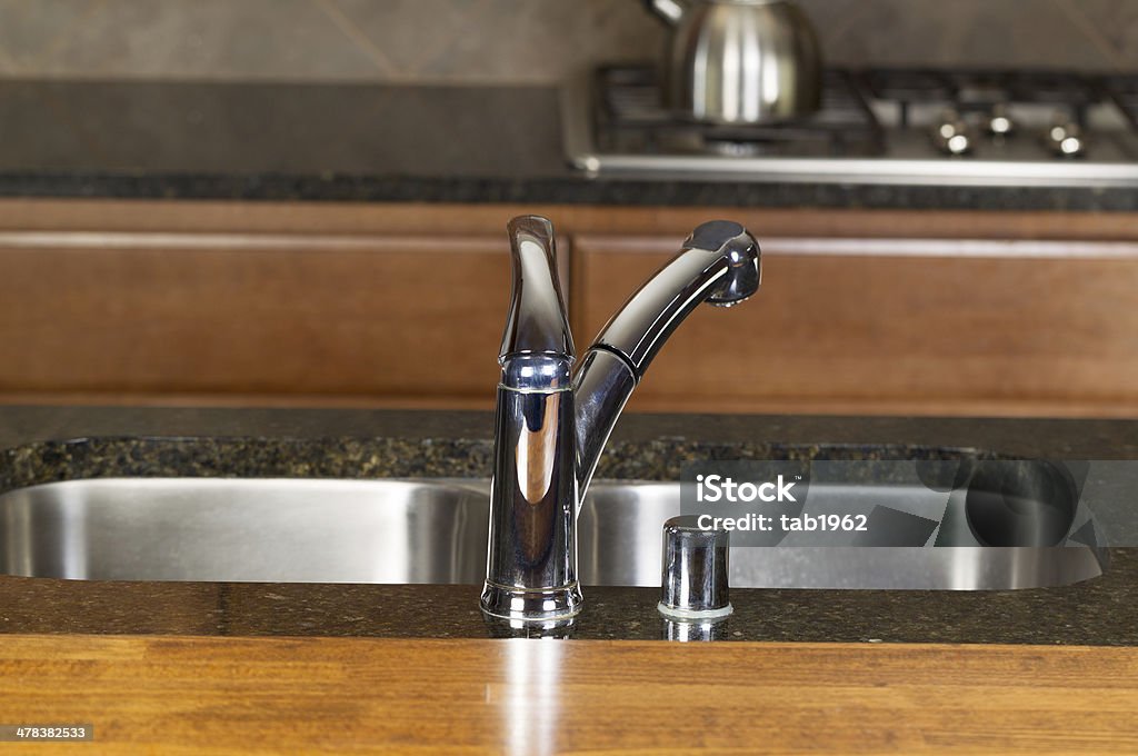 Chrome Kitchen Sink Faucet Horizontal photo of a chrome kitchen faucet with stone counter tops, cherry siding and range in background Cherry Wood Stock Photo