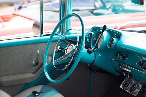 Vintage turquoise steering wheel at a car show.