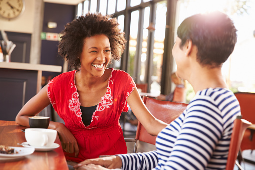 Dos mujeres amigos hablando en una cafetería photo