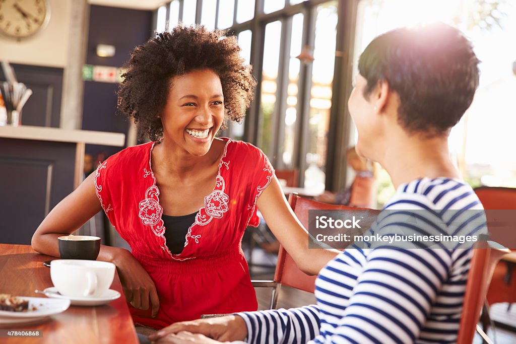 Two female friends talking at a coffee shop Discussion Stock Photo
