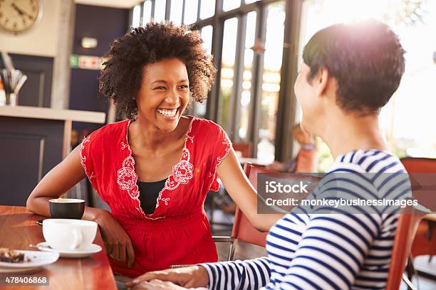 Two Female Friends Talking At A Coffee Shop Stock Photo - Download Image Now - Discussion, Talking, Friendship