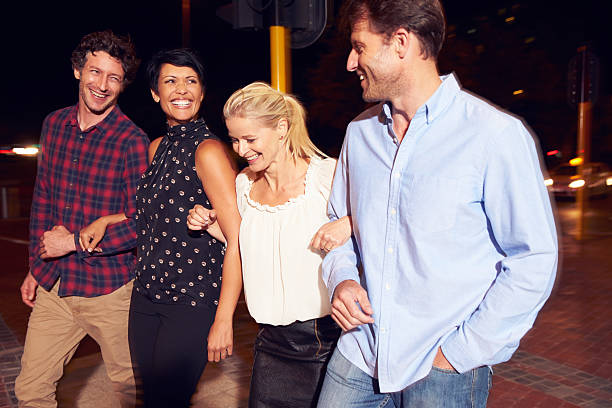 istock Four friends walking through town together at night 478406874