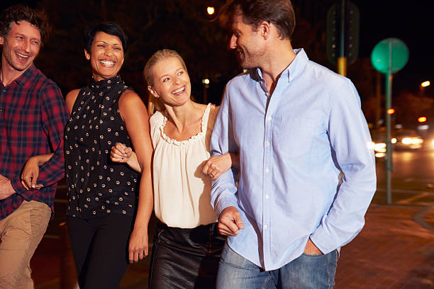 istock Four friends walking through town together at night 478406878