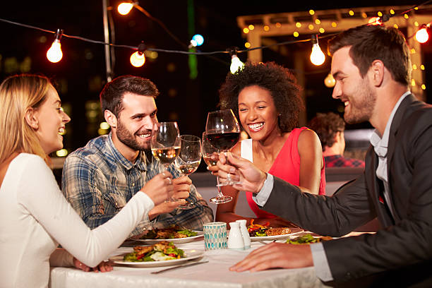 quatro amigos, comer o jantar no telhado do restaurante - refeição noturna imagens e fotografias de stock