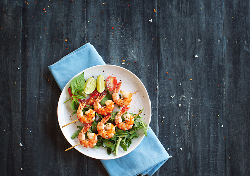 Grilled shrimps on skews with salad and lime slices