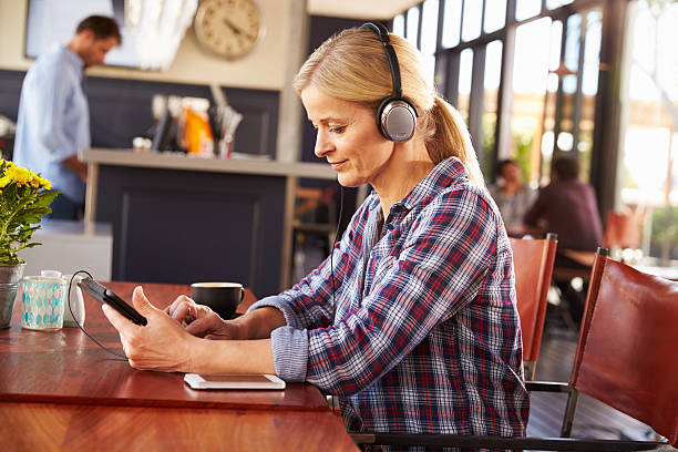 Woman with digital tablet at the coffee shop wearing headphones