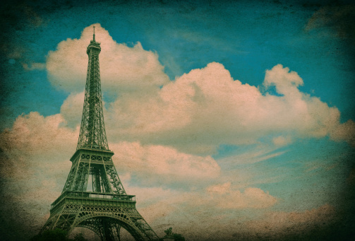Eiffel Tower (La Tour Eiffel) against cloudy blue sky. Champ de Mars, place of interest in Paris, Europe. Vintage style picture