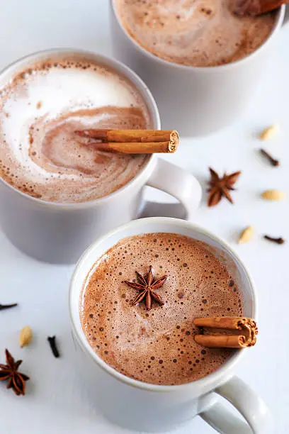 Cup of hot chai latte with spices like cinnamon, cardamon, cloves, star anise as a sweet warm winter dessert drink
