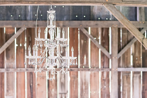 A beautiful crystal chandelier hanging in a rustic wooden barn 