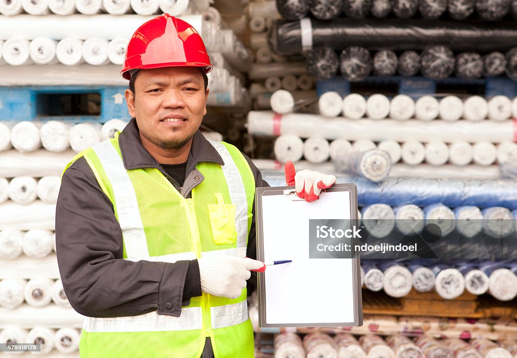 Textile factory worker Textile factory worker presenting a clipboard and pointing with a pen 2015 Stock Photo