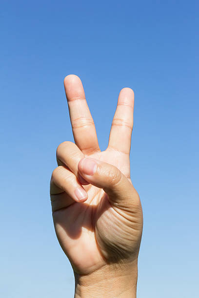 istock Hand showing victory sign on sky background 478418838