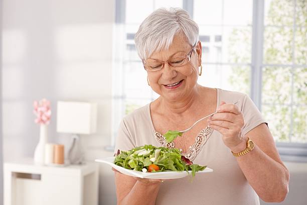 Vecchia donna mangiare Insalata verde - foto stock