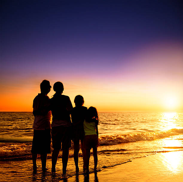 istock happy family watching the sunset on the beach 478426086