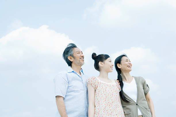 空に背を向けて立つ家族 - 家族　笑顔 ストックフォトと画像