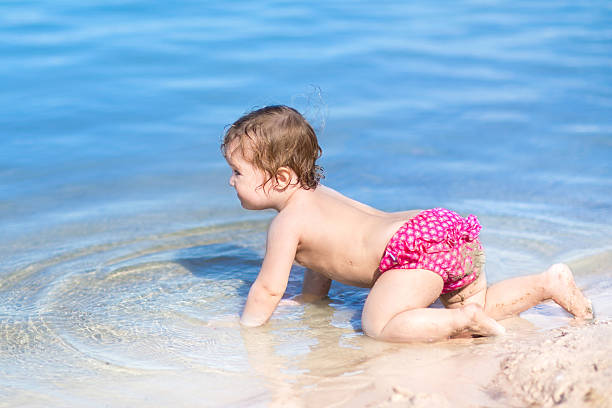 Cute baby crawling on beautiful beach with clear blue water Cute little baby crawling on a beautiful beach with clear blue water backside for a girl on the beach stock pictures, royalty-free photos & images