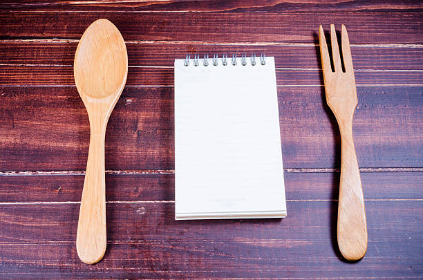 istock Notebook with wooden spoon and fork  on wooden background 478428618