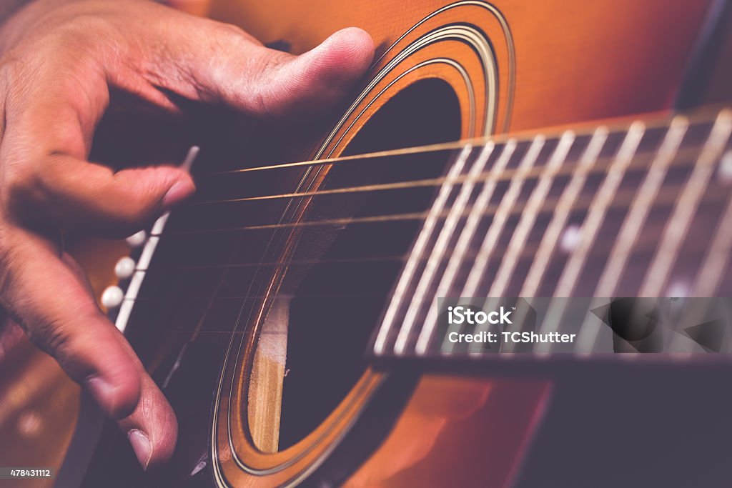 Guitarist Tending to his Instrument Guitarist playing with his guitar. Acoustic Guitar Stock Photo