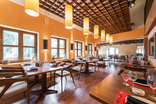 Cafe restaurant interior with wooden furniture, lighting equipment and decoration and setting table