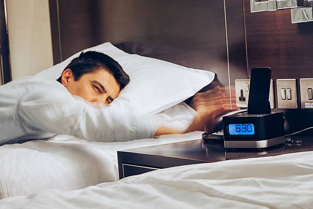 Wake Up Early Time Businessman sleeping on bed and his hand reaching to turn off alarm clock with speedy action at 6:30 AM, Wake up early morning concept oversleeping stock pictures, royalty-free photos & images