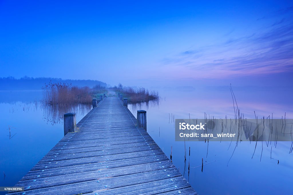Boardwalk over water at dawn in The Netherlands A boardwalk over a still lake on a quiet morning at dawn, near Amsterdam in The Netherlands. 2015 Stock Photo