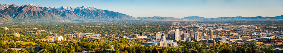 Blue skies and snow capped mountains above the landmarks of Salt Lake City, from the leafy suburbs and University campus to the monument dome of the State Capitol and the ornamental spires of the Mormon Temple surrounded by the skyscrapers of downtown, Utah, USA. ProPhoto RGB profile for maximum color fidelity and gamut.