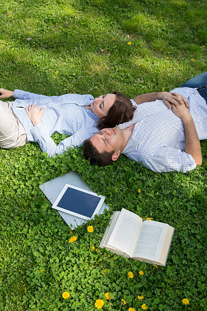 istock Young man and woman napping on grassy lawn 478443948