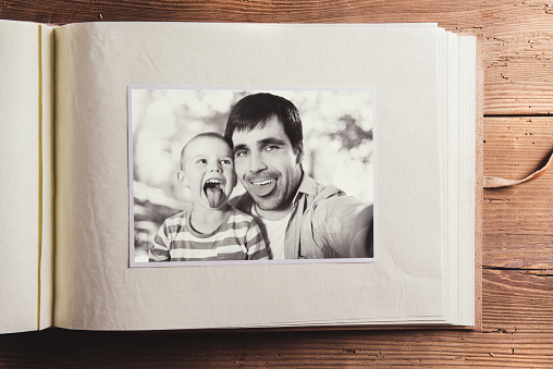 Fathers day composition - photo album with a black and white photo. Studio shot on wooden background.
