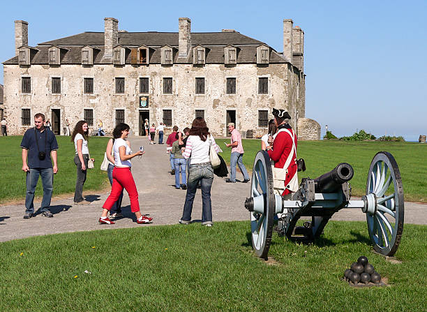 Fort Niagara, NY, USA - September 11, 2005: Volunteers and tourists participating in historical event in Old Fort Niagara. In front cannon with balls, at background French Castle.