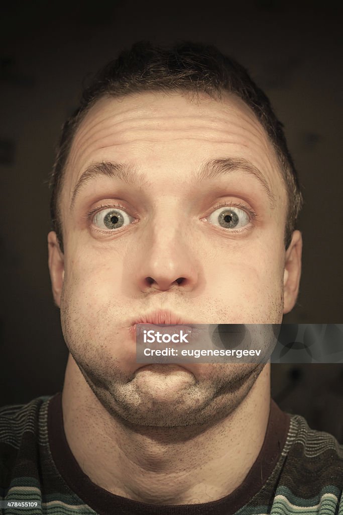 Young funny Caucasian man inflates cheeks. Closeup portrait Cheek Stock Photo