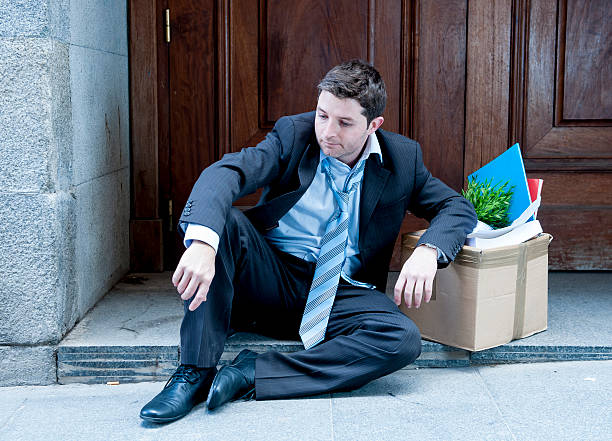 istock frustrated business man on street fired carrying cardboard box 478457757