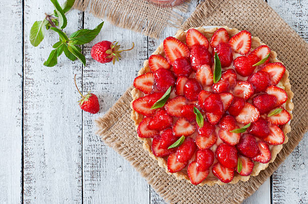 tarte avec des fraises et crème fouettée décorées avec des feuilles de menthe - tarte sucrée photos et images de collection