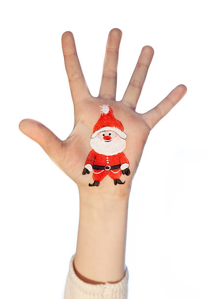 Kid's hands with painted Christmas symbol. Santa
