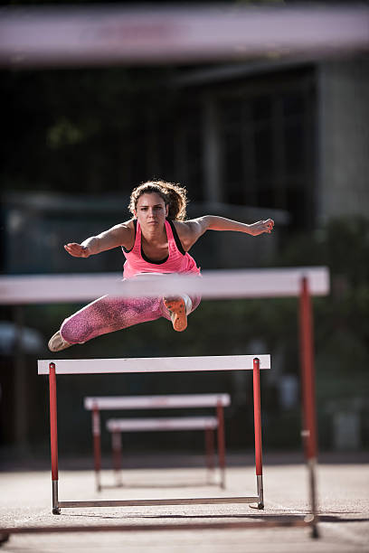 istock Determined female athlete jumping hurdles on a race. 478477498