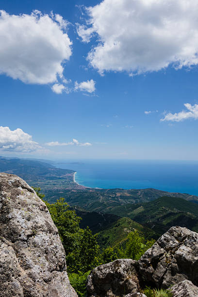 Aerial top view of green hill and harbour of beautiful seaside town village Scilla, Tyrrhenian sea bay gulf coast shore, Sicilia island and blue sky background, Calabria, Southern Italy