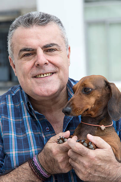 istock Attractive Senior with white beard Playing with dachshund dog 478484628