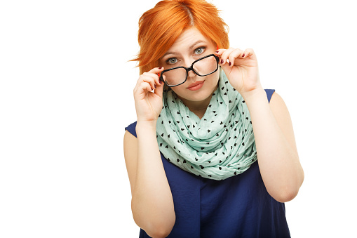 Portrait of surprised red-haired young woman holding glasses on her nose isolated on white background