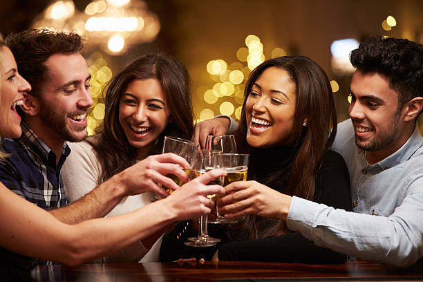 gruppo di amici, godersi un drink serale al bar - friendship drinking beer group of people foto e immagini stock