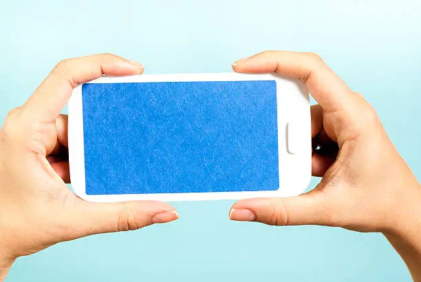 Photo of Hands showing a blue horizontal mobile phone concept on blue background