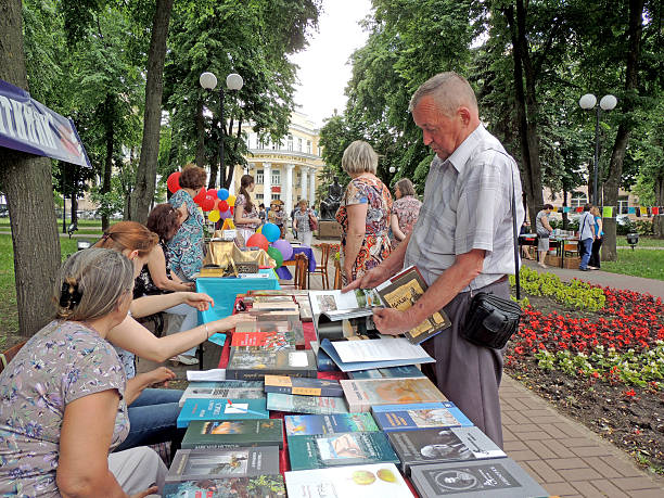 Voronezh, Russia - May 27, 2015: Mature men chooses books on the stall to buy them on the book fair in the public garden