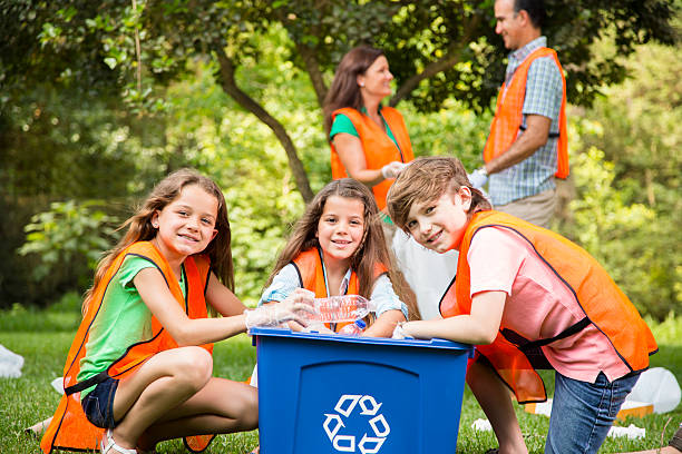Happy young Asian students diverse volunteers with garbage bags cleaning area in the park, The concept of environmental conservation on world environment day, recycling, charity for sustainability.