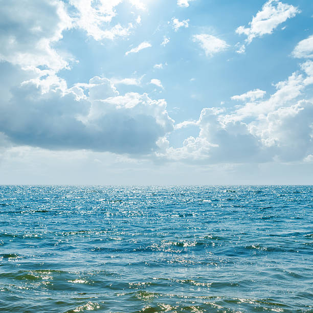 istock blue sea with sun in clouds 478507818
