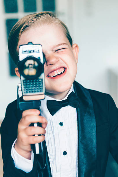 istock Boy in tuxedo makes movie with old video camera 478513834