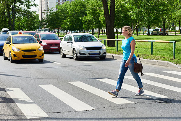 Woman crossing street at pedestrian crossing Woman crossing the street at a pedestrian crossing zebra crossing photos stock pictures, royalty-free photos & images